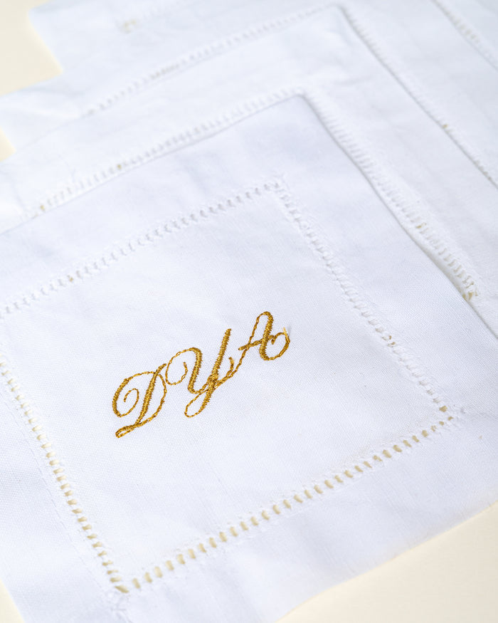 Gold monogram stitched into a white linen napkin