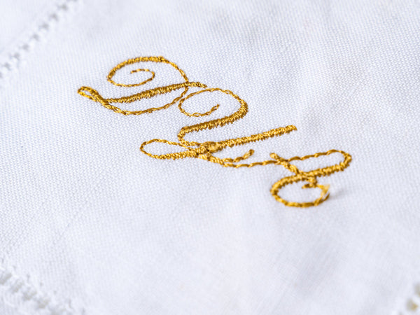 Gold monogram embroidered on a white linen napkin