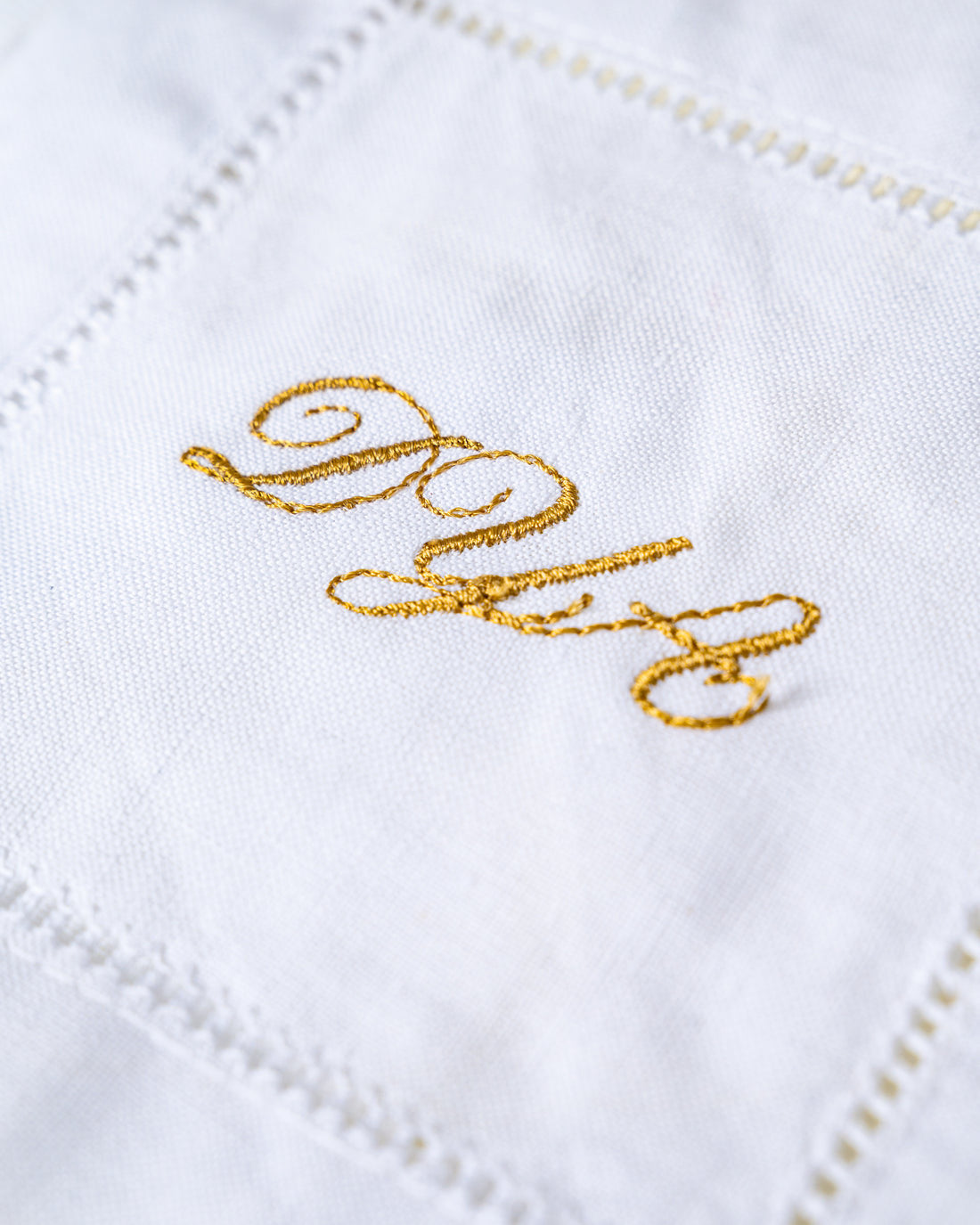 Gold monogram embroidered on a white linen napkin